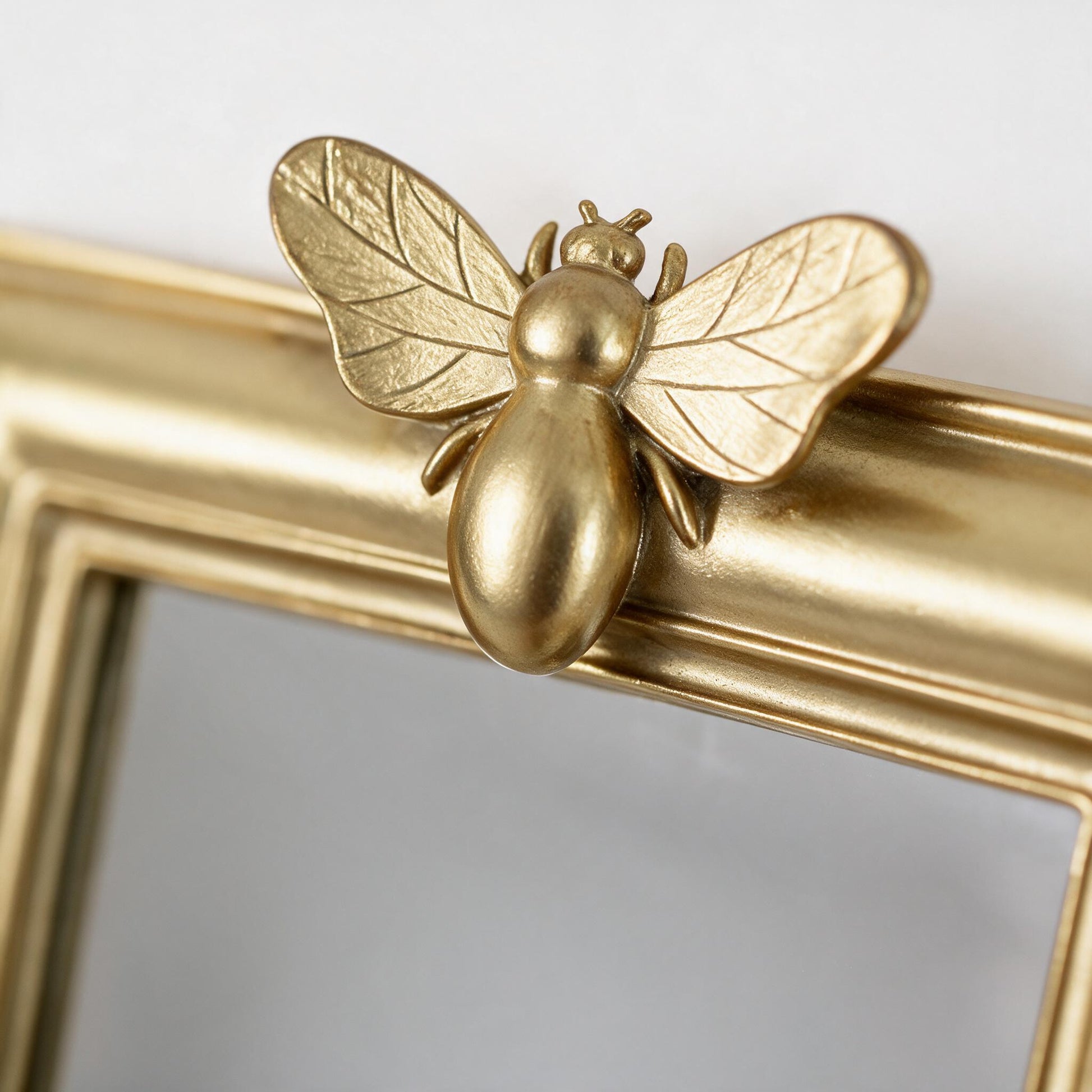 Close-up detail of the gold bee motif on the Lumara Bee Mirror frame
