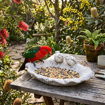 Two birds leaf bird bath in garden setting