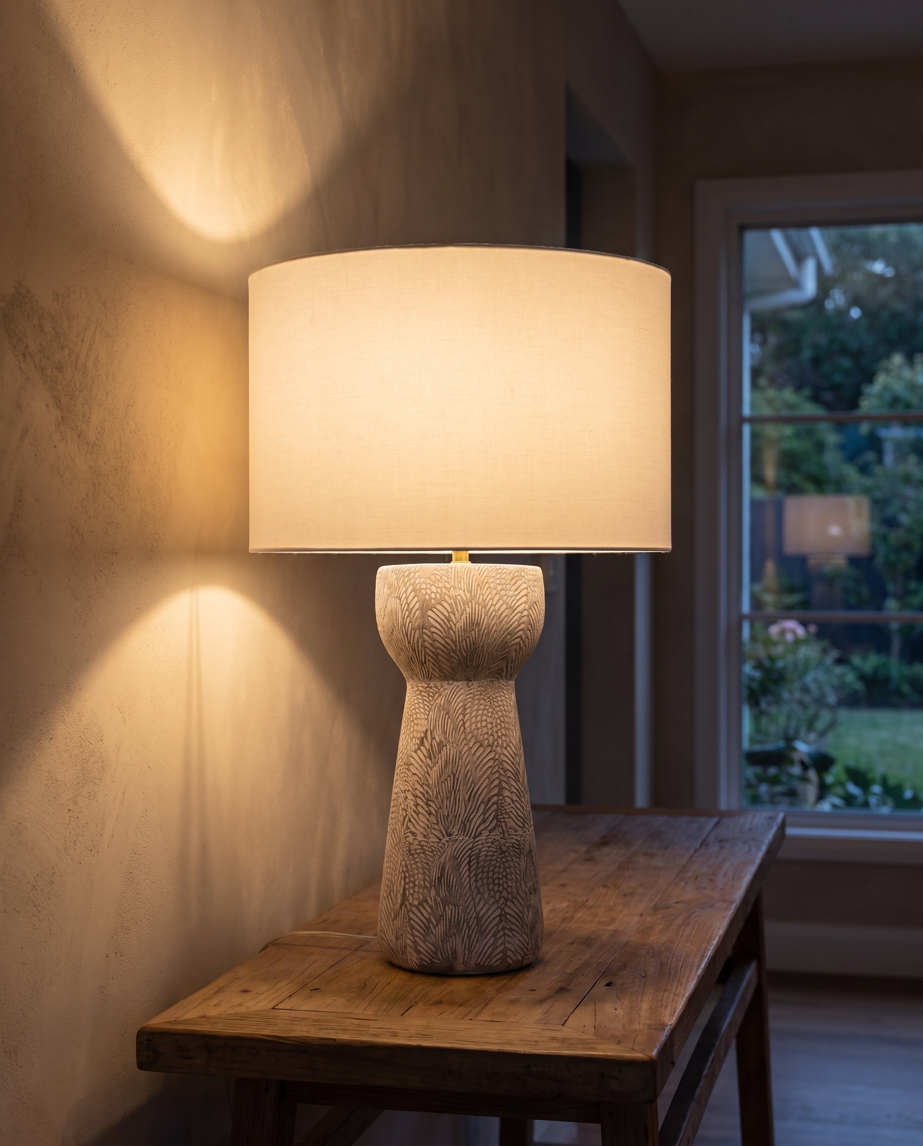 Lumara Fossil Table Lamp lit at dusk against a limewashed wall — Lumara Home