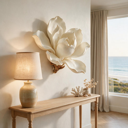 Magnolia XL sculpture hung above an oak console with a ceramic lamp casting light across the petals — Lumara Home