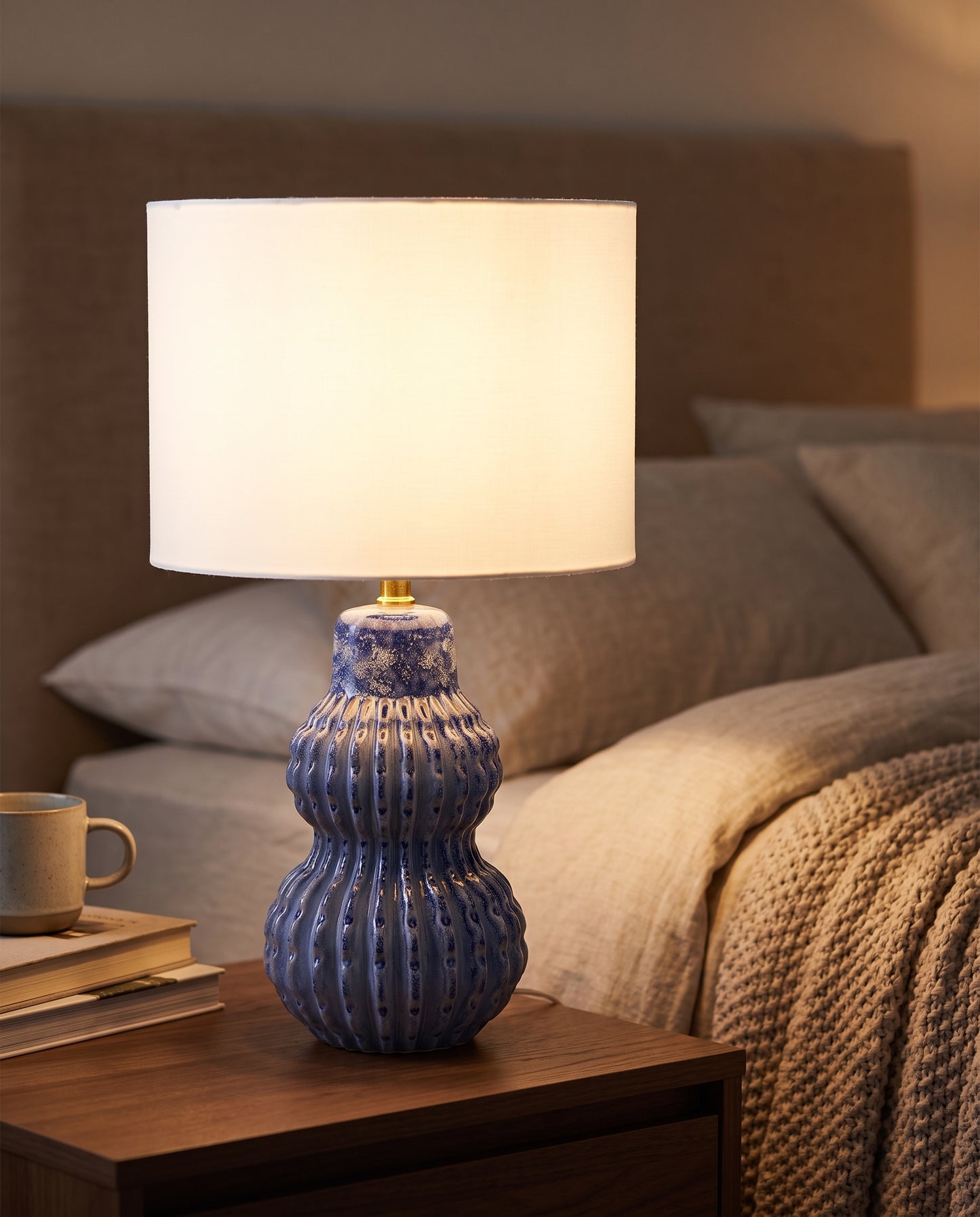 Malabar Table Lamp ocean blue glowing at dusk in a bedroom — Lumara Home