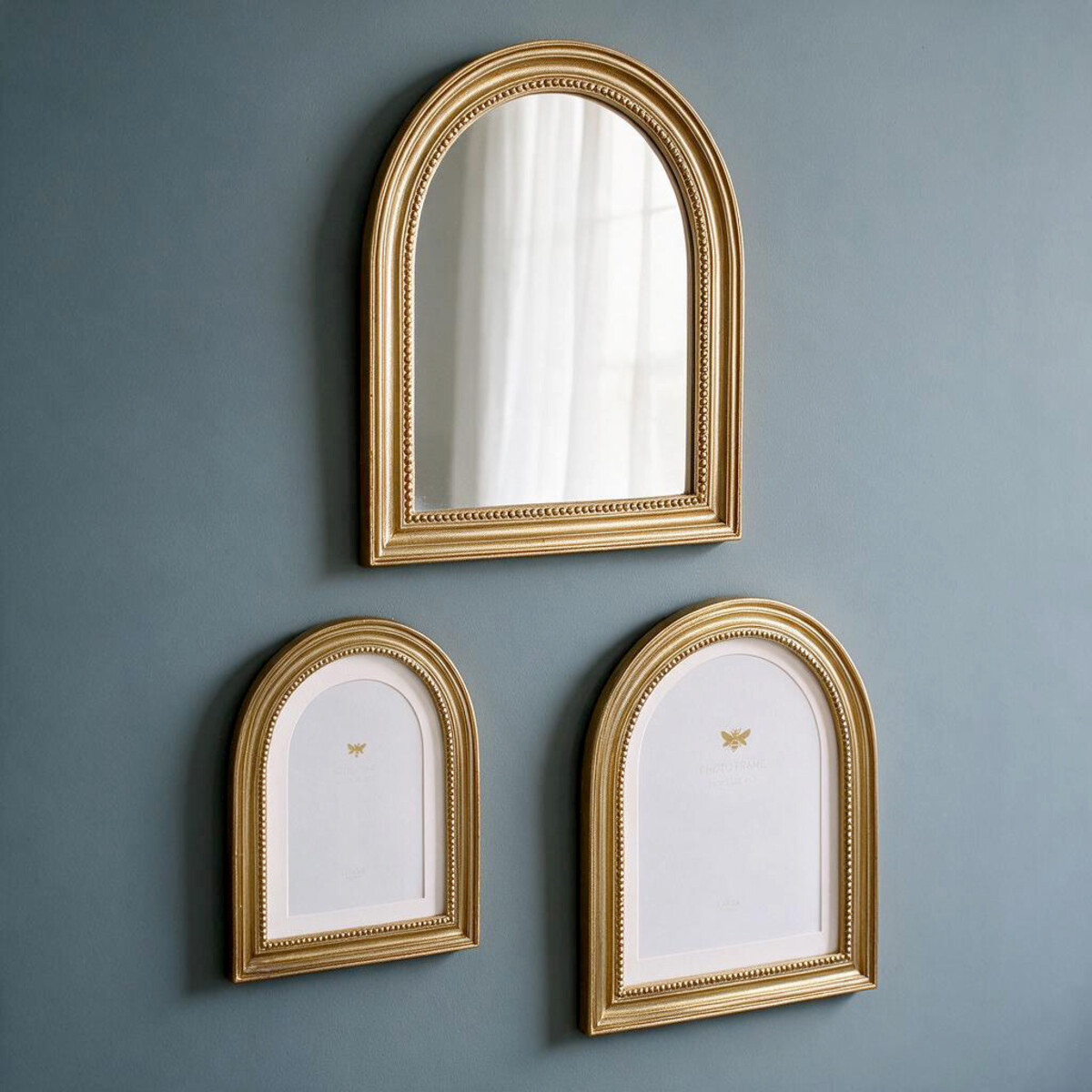Lumara Marbella Arch Mirror at true scale on a blue wall above two matching arched photo frames